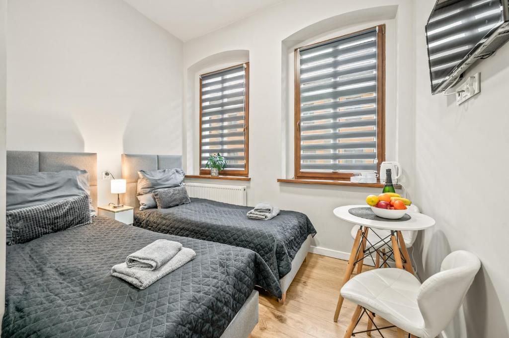a bedroom with two beds and a table with a chair at Central Platinum Apartments 1 in Rybnik