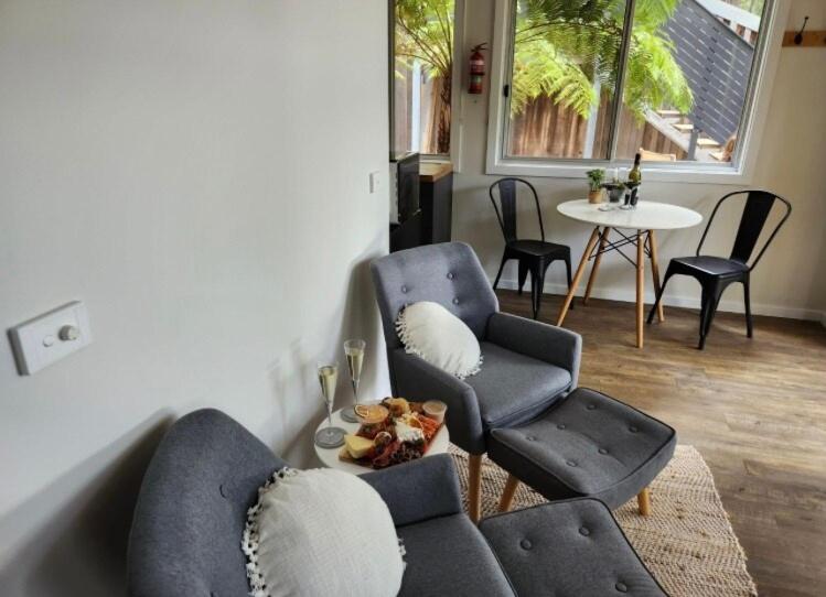a living room with a couch and chairs and a table at Noojee views - cozy studio in Noojee