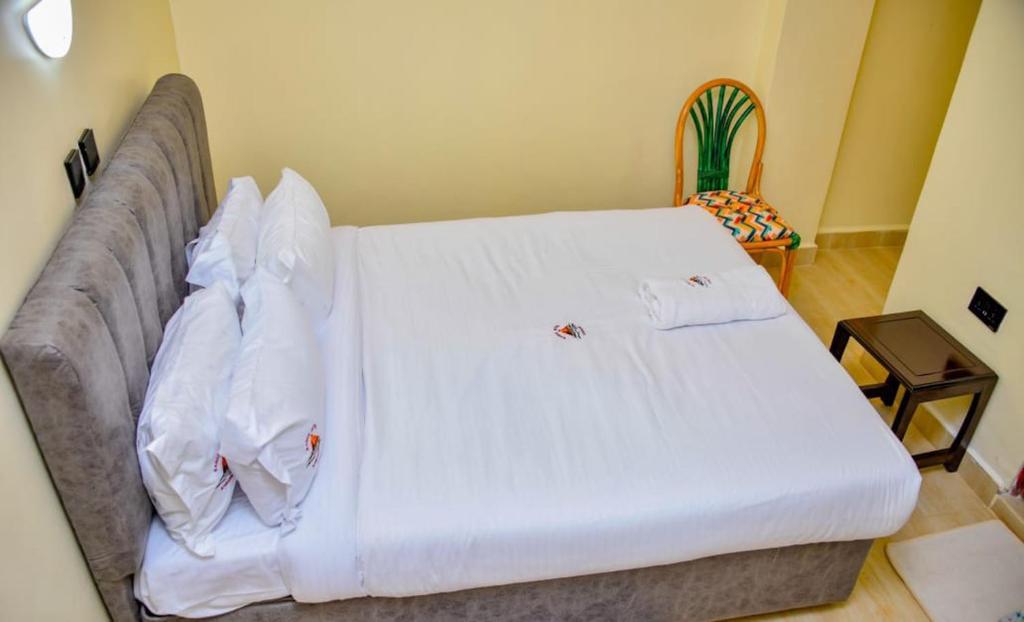 a large bed with white sheets and pillows on it at Saimo Hotel-Kabarnet in Kabarnet