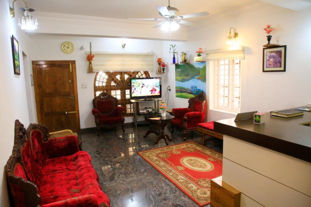 a living room with red chairs and a tv at Avalan Resort Homestay in Thekkady