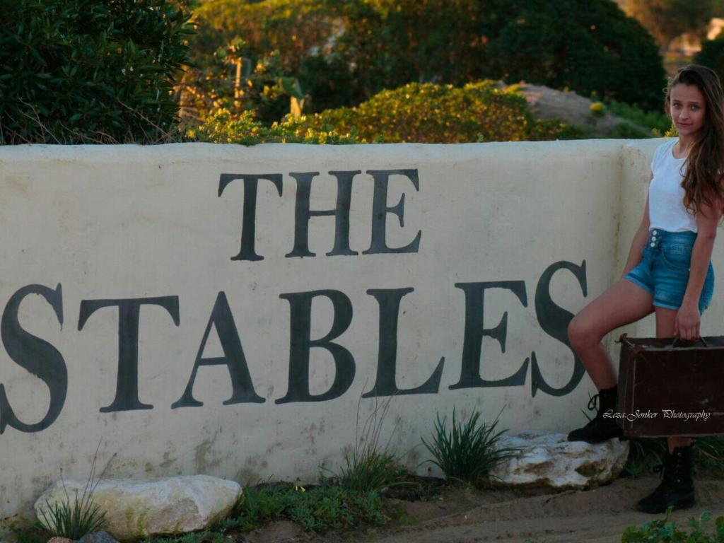 a woman is standing in front of a sign at The Stables in Langebaan