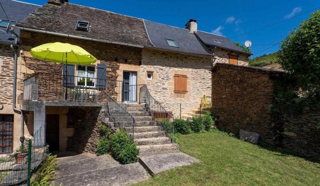 a stone house with an umbrella in front of it at Gîte de Malavals in Castelnau-de-Mandailles