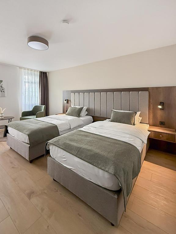 a hotel room with two beds and a chair at STADT-Hotel Lörrach GbR in Lörrach