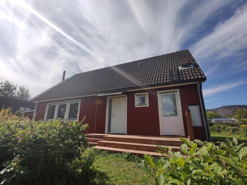 a small red house with a white door and porch at Villa Stolle in Hammarstrand