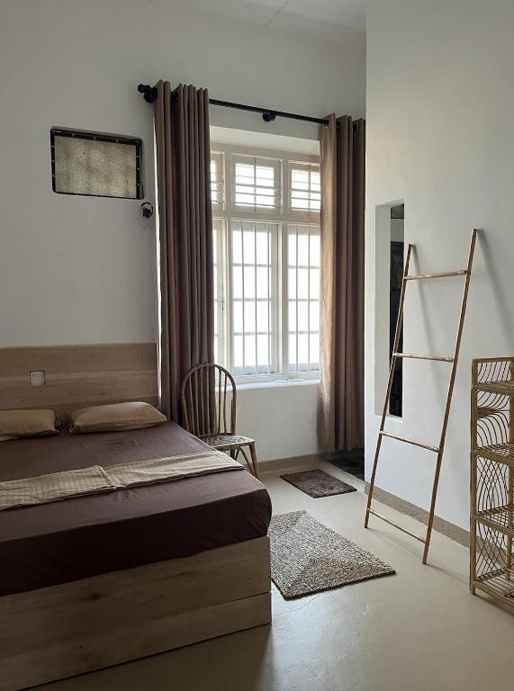 a bedroom with a bed and a ladder and a window at Papaya Tree Hostel in Weligama