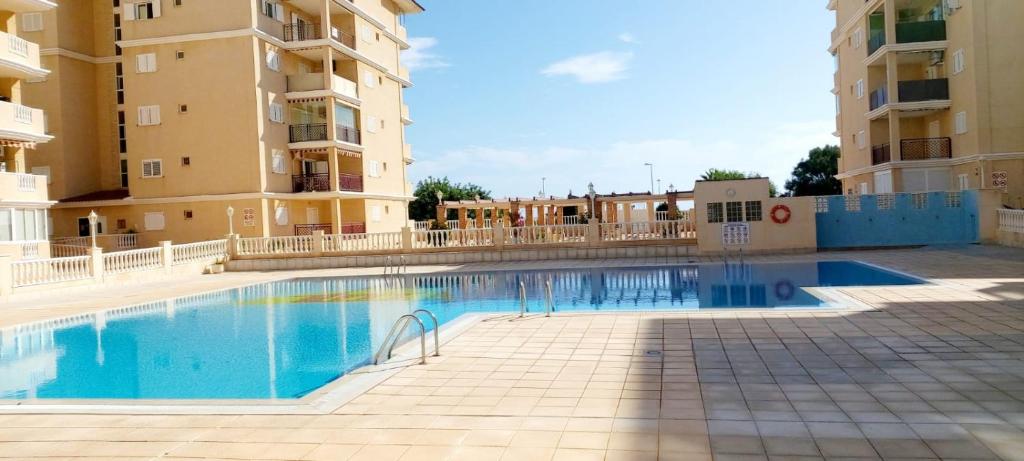 a swimming pool in the middle of two apartment buildings at SOLMAR La Mata Beach in Torrevieja