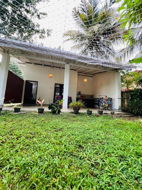 a house with a green lawn in front of it at Lagoon Home Stay in Ahangama