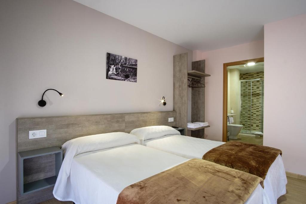 ein Schlafzimmer mit 2 Betten und ein Badezimmer in der Unterkunft Albergue Pensión Cima do Lugar in Arzúa