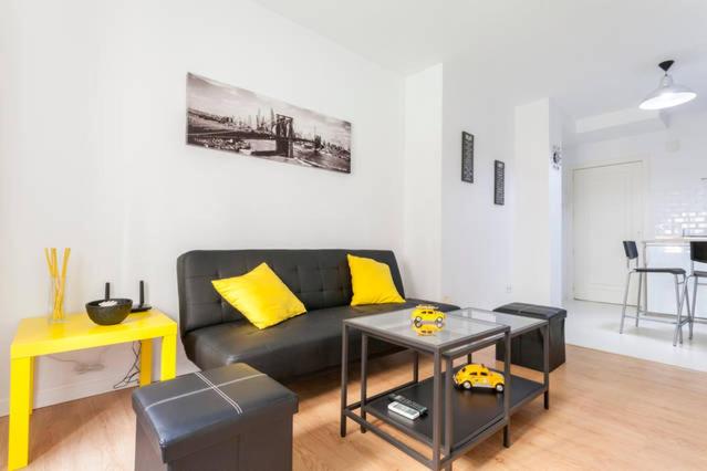 sala de estar con sofá negro y almohadas amarillas en Villa de Indias, en Sevilla