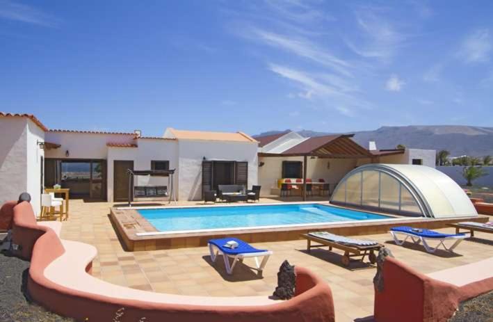 een zwembad in een tuin met een huis bij Villa Vista Graciosa in Las Laderas