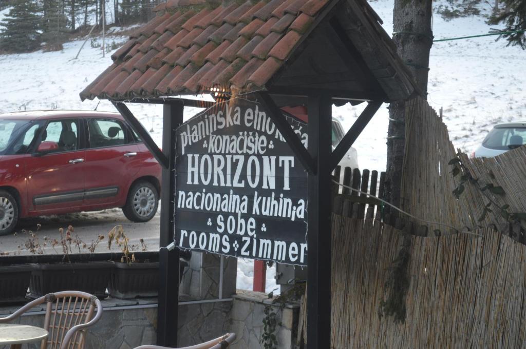 a sign in front of a building with a roof at Guest House Vila Horizont in Goč