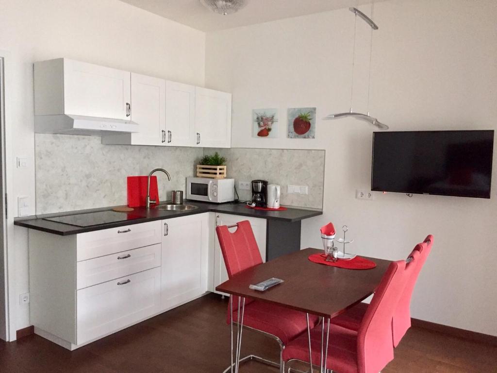 a kitchen with a table and red chairs in a kitchen at Apartment am Zwingerteich in Dresden