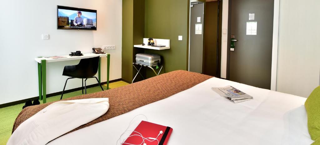 a hotel room with a bed with a tv on the wall at Central Park Hôtel & Spa in La Rochelle