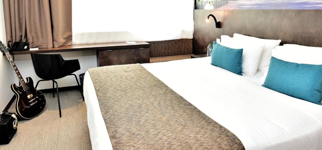a bedroom with a bed and a guitar in a room at Central Park Hôtel & Spa in La Rochelle
