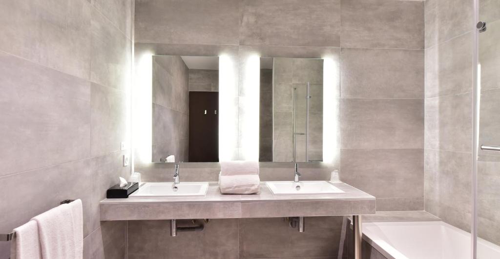 a bathroom with two sinks and a mirror at Central Park Hôtel & Spa in La Rochelle