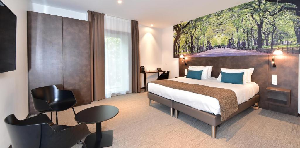 a hotel room with a bed and a painting on the wall at Central Park Hôtel & Spa in La Rochelle