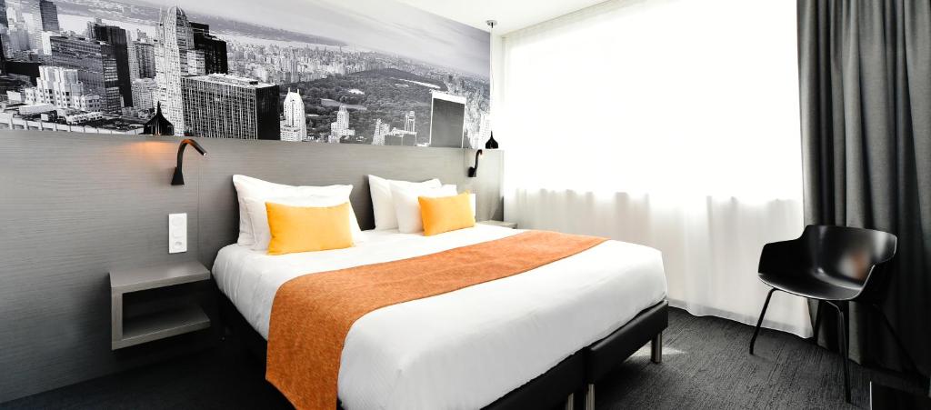 Habitación de hotel con cama grande con almohadas de color naranja en Central Park Hôtel & Spa en La Rochelle