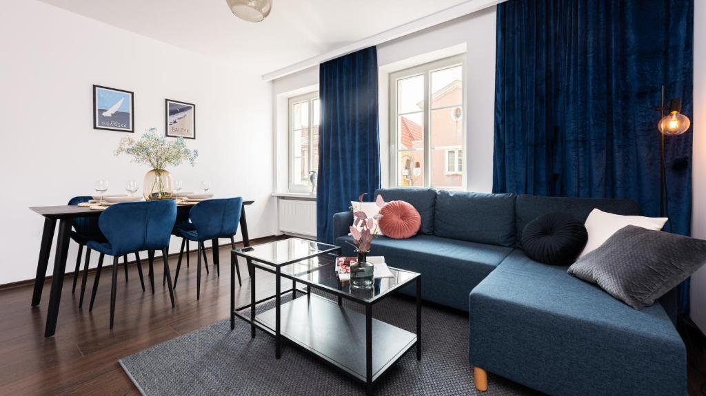 a living room with a blue couch and a table at Flatbook Comfort Old Town 8 in Gdańsk