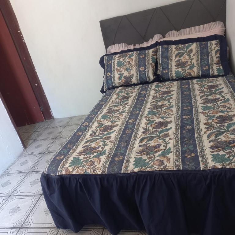 a bed with a blue comforter and pillows on it at Suíte in Garopaba