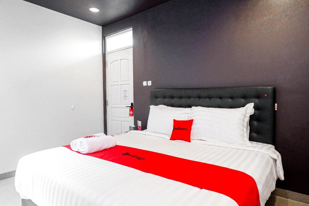 a bedroom with a large white bed with red accents at RedDoorz near Bukitsari Semarang in Jatingaleh