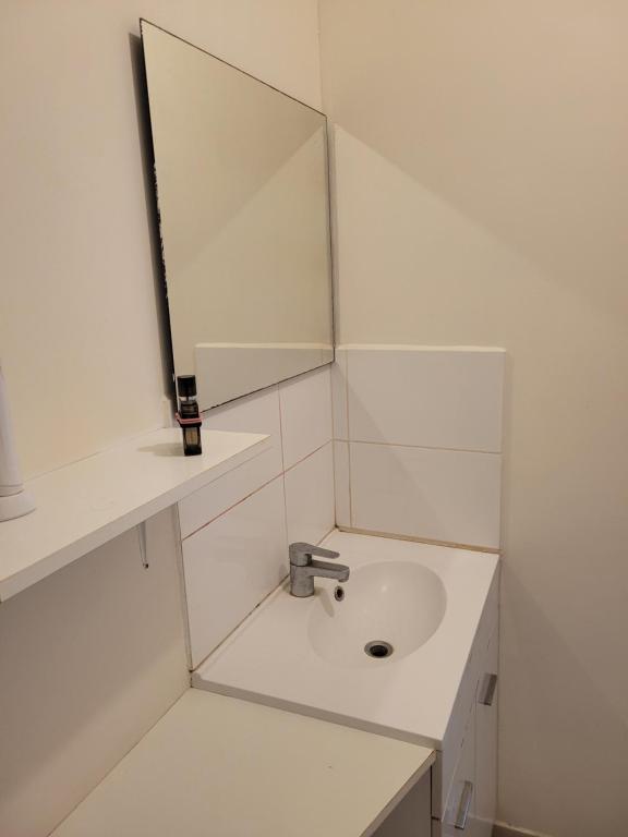 a white bathroom with a sink and a mirror at Lieu charmant in Gimeux