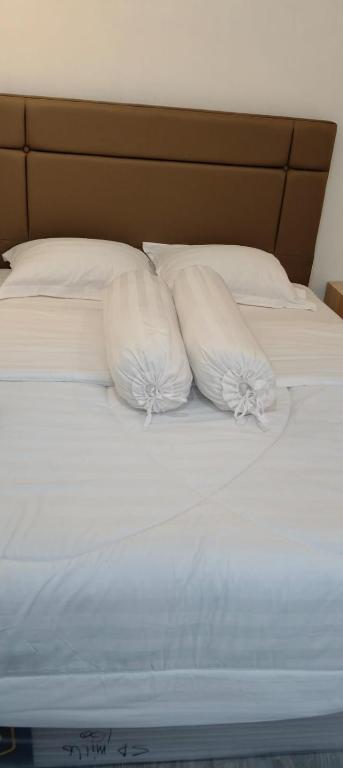 two pillows on a bed with white sheets at MEWAH guest house in Karangploso