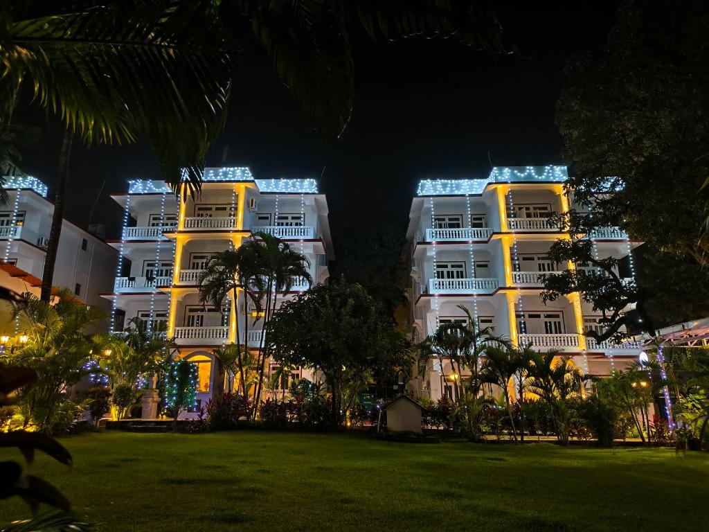 two large white buildings at night with a park at Maashpi Hotel & Resort, Candolim in Candolim