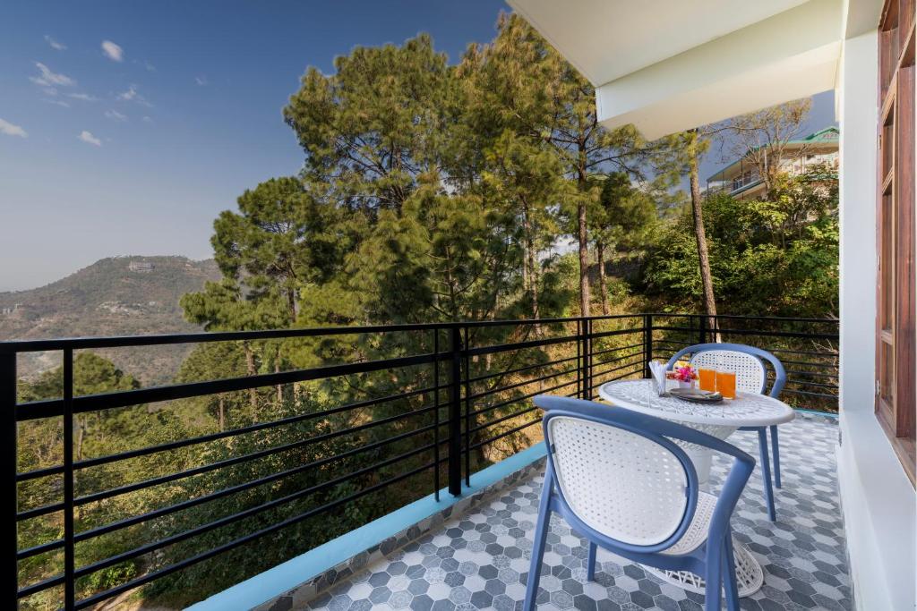 a balcony with a table and chairs and a view at Kasauli Hills Hotel in Kasauli