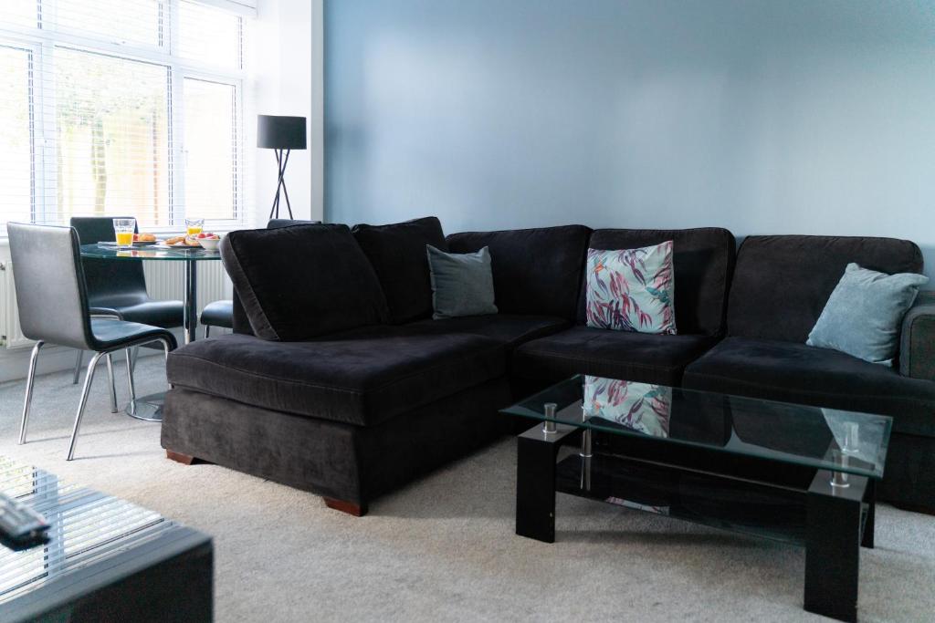 a living room with a black couch and a table at Spacious and Comfortable - 5 Bedroom Home in Kettering