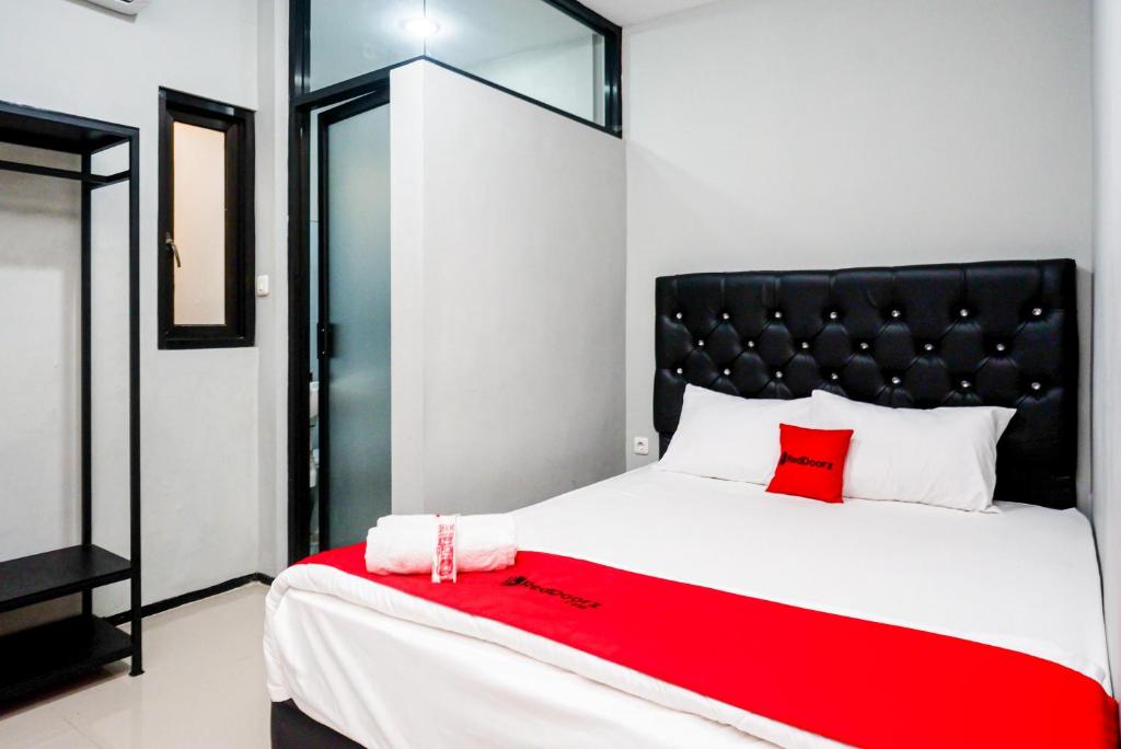 a bedroom with a large bed with a red blanket at RedDoorz Plus @ Kalpataru in Rampal