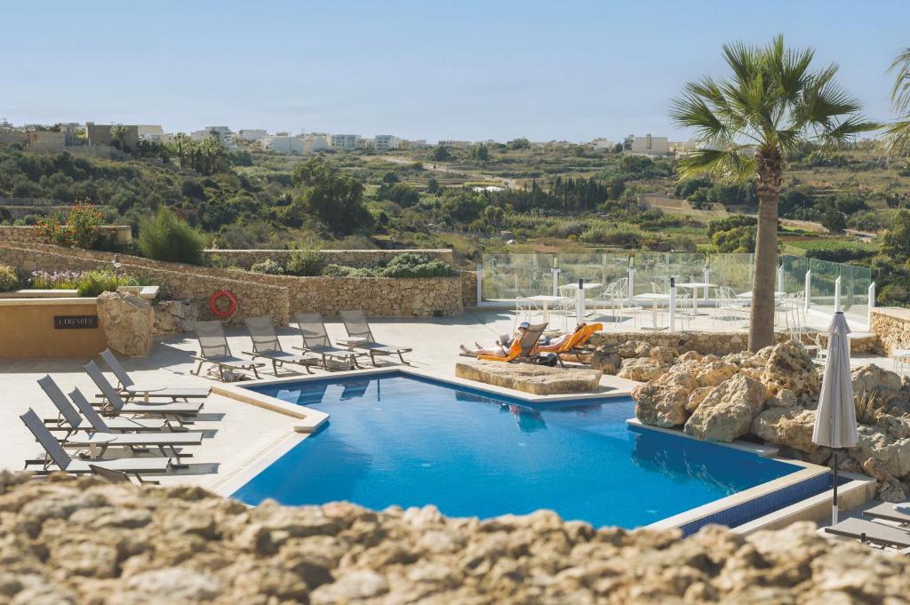 a swimming pool with lounge chairs and a resort at L-Eremita Boutique Hotel in Qala