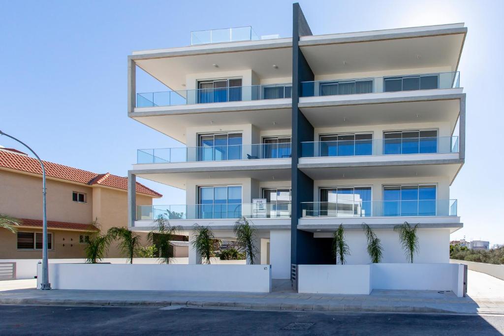 an apartment building with palm trees in front of it at BlueBell Limassol Suites in Limassol