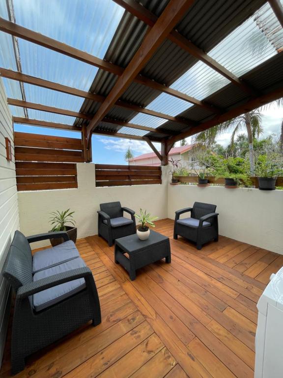 a covered patio with furniture and a wooden floor at Les volets de l'océan in Saint-Philippe
