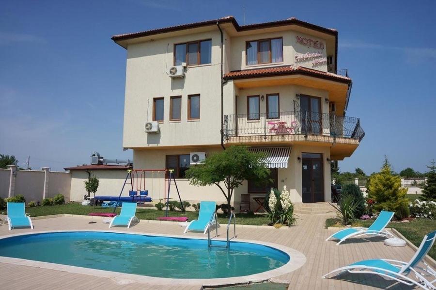 a building with a pool in front of a house at Златна люспа in Bŭlgarevo