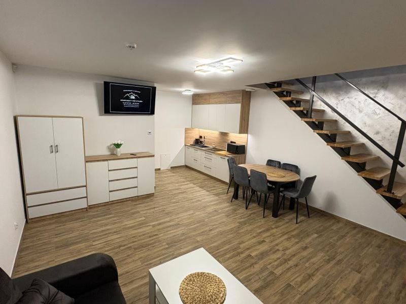 a living room with a staircase and a table and chairs at Apartamenty w Kotlinie in Lądek-Zdrój