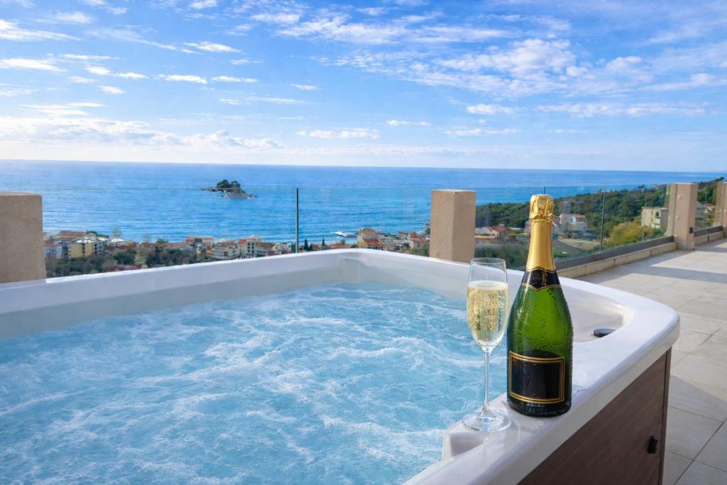 a bottle of champagne and two wine glasses in a hot tub at Villa Blue Vista Meerblick mit Jacuzzi in Petrovac na Moru