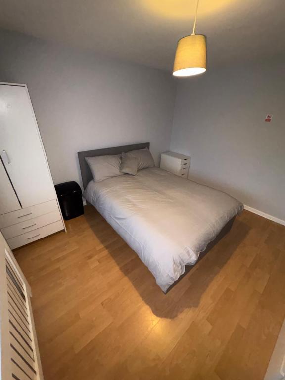 a bedroom with a white bed and a wooden floor at Cosy room 4 T Gatwick in Crawley