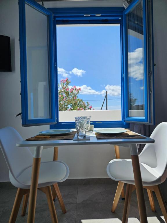 a table with two chairs and a large window at Parian Nissos Harmony Living in Angairiá