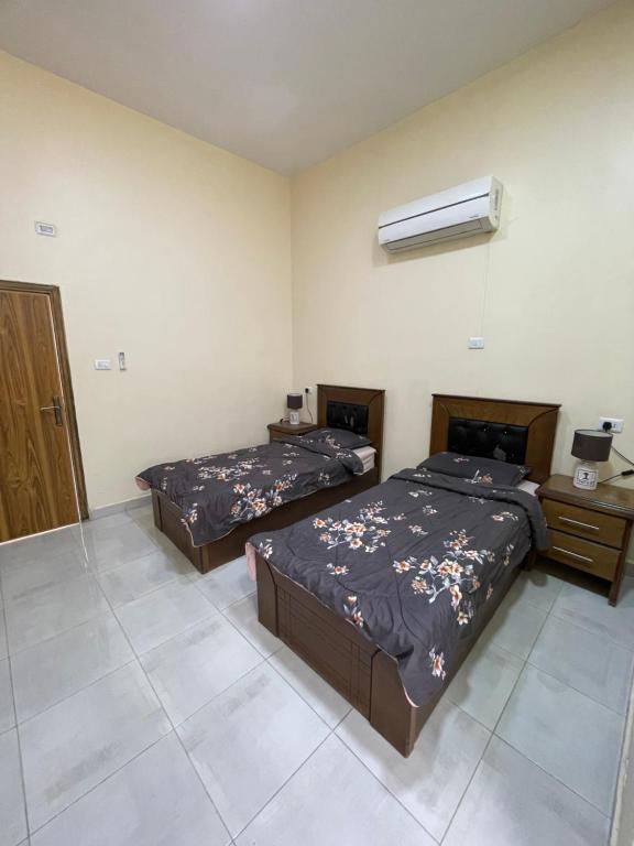 a bedroom with two beds and a air conditioner at Petra 555 Rooms & Apartment in Wadi Musa