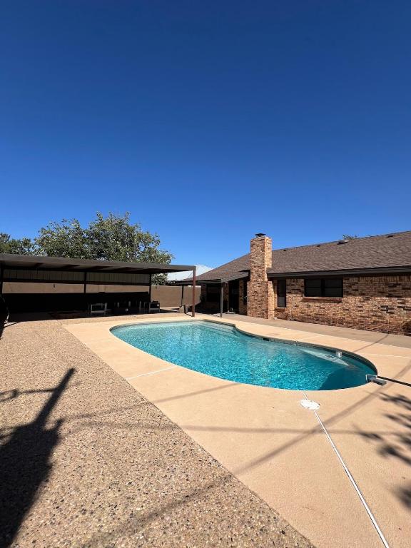 a swimming pool in front of a house at Midland Luxe, Pool, Fire Pit, Workspace, Pool Table in Midland