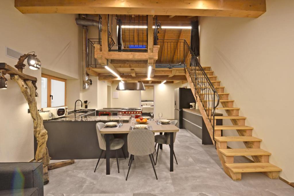 a kitchen and dining room with a wooden staircase and a table at ArtiStone - "The Modern Loft" - Nature and Relax in Saint-Christophe