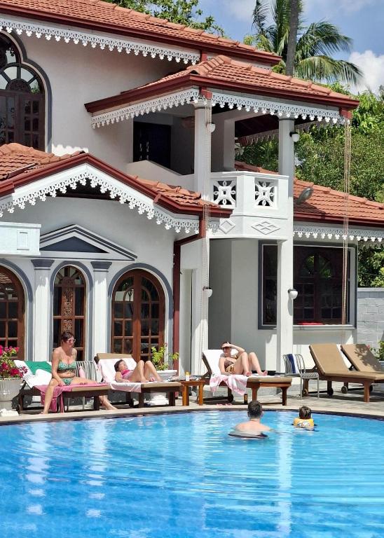 a group of people laying on chairs in a swimming pool at Yahana Beach Villa in Negombo