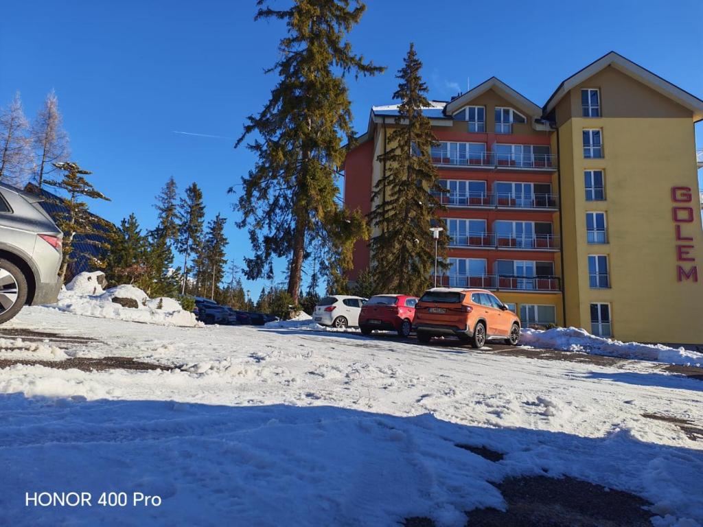 two cars parked in front of a hotel in the snow at Tatra Frank Apartman in Štrba