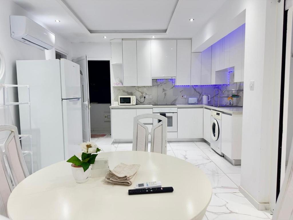 a white kitchen with a white table and chairs at Lumière Retreat 2 in Larnaca