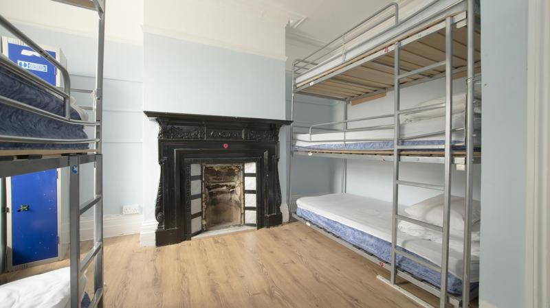 Pokój z kilkoma łóżkami piętrowymi i kominkiem w obiekcie Queen Elizabeth Hostel w Londynie