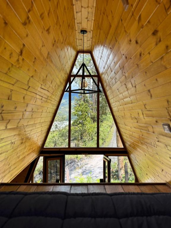 a room with a large window in a wooden wall at Finca Milele in Macanal