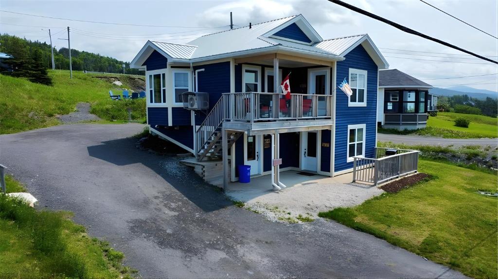 a blue house with a balcony on a driveway at Drift Ashore House in Rocky Harbour