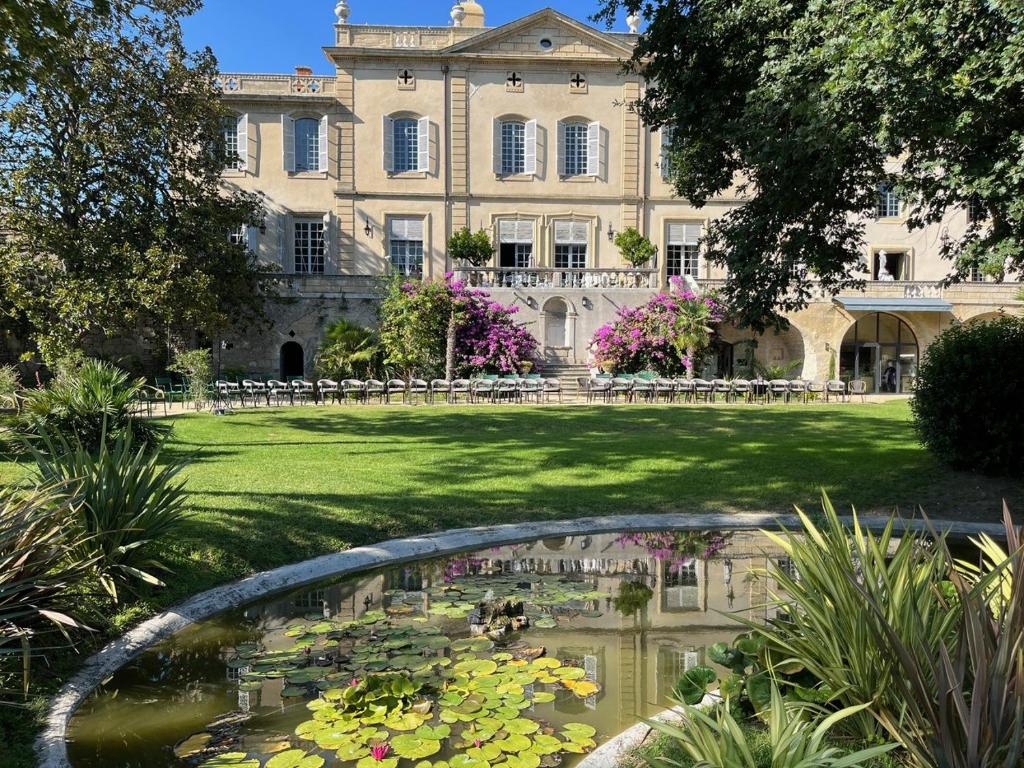 a large house with a pond and a building with flowers at Château de Collias - Maison de Vacances in Collias