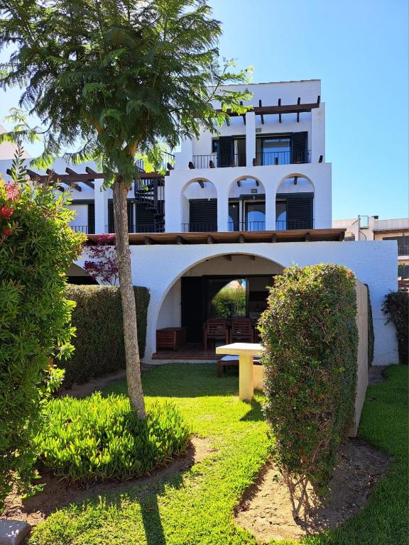 a white house with a palm tree and a bench at Les Oliveres Beach in Perelló