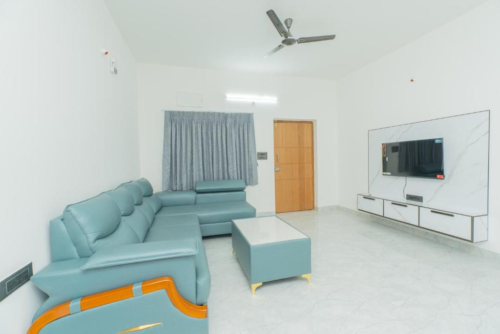 a living room with a blue couch and a tv at Aikya Service Apartment in Hyderabad